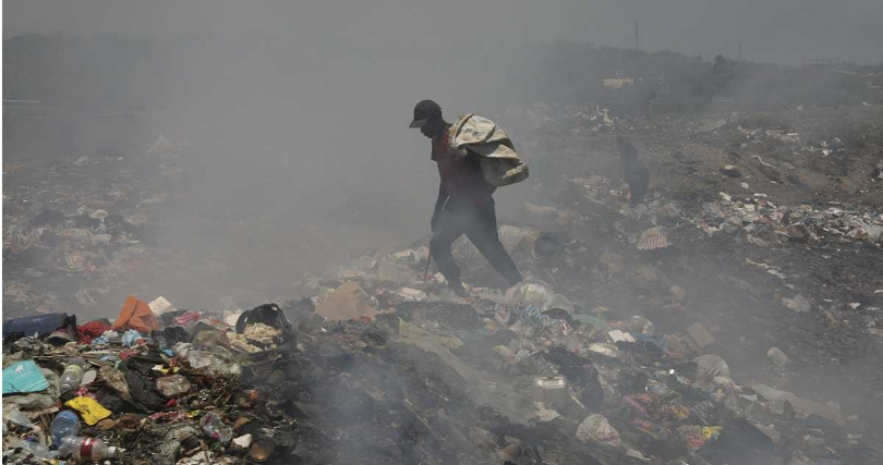 一名男子在海地太子港的垃圾掩埋場找有用的物品。
