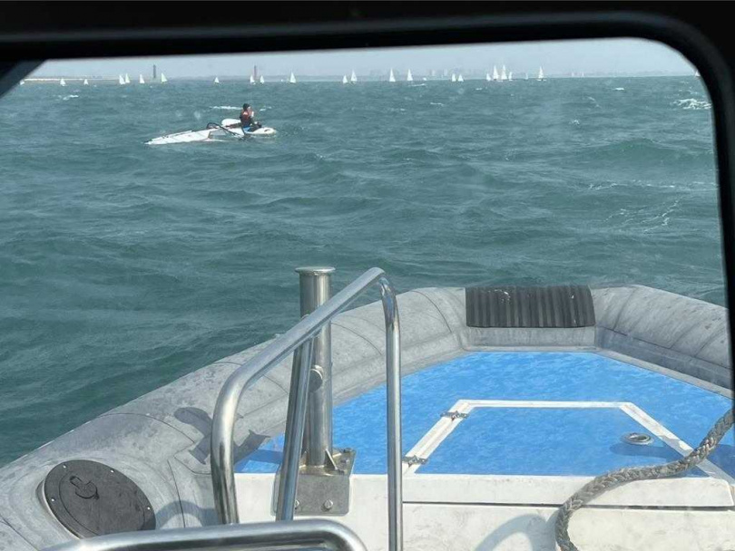 海巡人員在海域發現學童趴在風帆上向巡防艇招手請求救援。（圖／讀者提供／曹婷婷台南傳真）