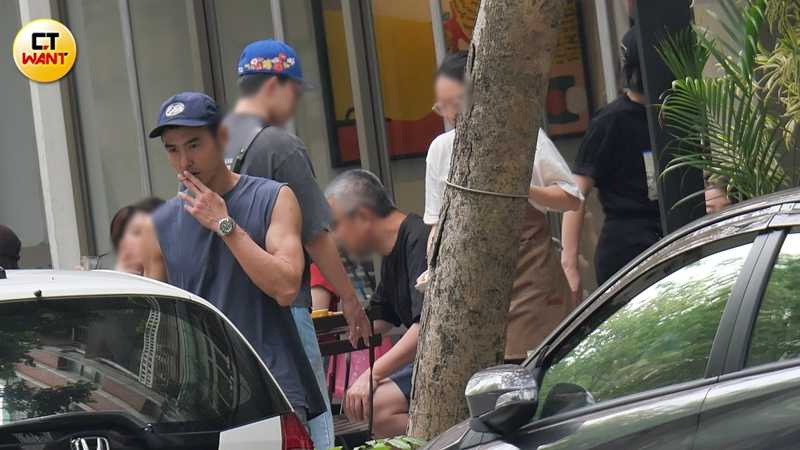 身穿無袖上衣的阮經天露出健身有成的手臂，不時撇頭到一旁抽菸。（圖／本刊攝影組）
