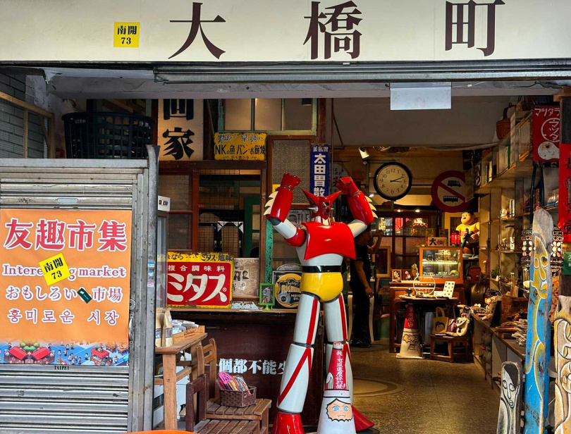 「大橋町」門口偌大的無敵鐵金剛公仔吸引不少大人小孩駐足合影。（圖／吳德亮攝影）