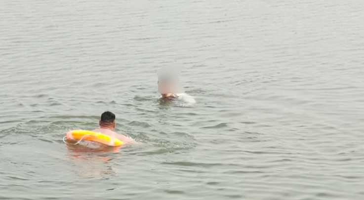 汽車失控墜入湖中,正值生死關頭,一名男子用嘴巴叼住撬棍,脫下衣服跳進湖中,砸破車窗救人。(圖/翻攝自微博)