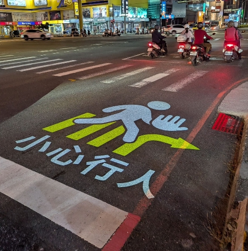 警示系統透過投影燈光，在地面投射"小心行人"的文字，搭配亮黃色標線，讓駕駛從遠方就能看見，提前減速。（圖／翻攝畫面）
