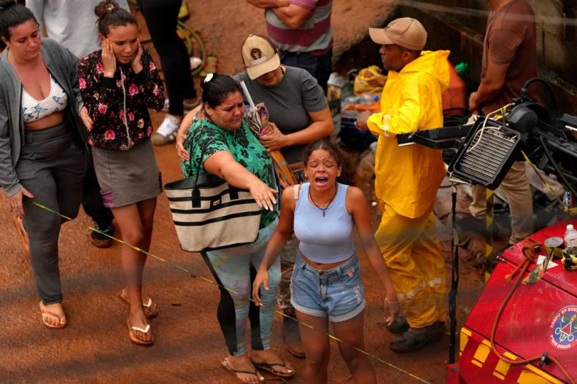 居民站在受損住宅前查看災情，神情凝重哀戚。