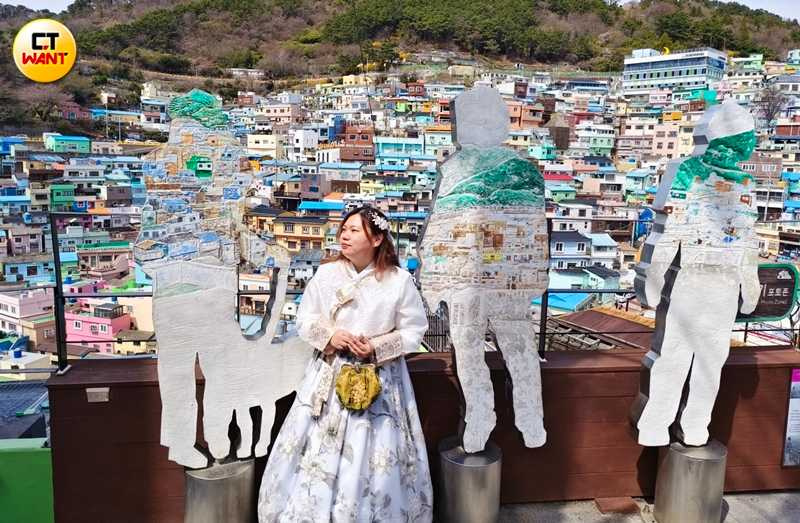 在甘川洞文化村入口附近有個知名打卡點「和甘川合而為一」，從特定角度可拍攝3個人形立牌上所繪景象與真實房屋群融為一體的畫面。（圖／魏妤靜攝）