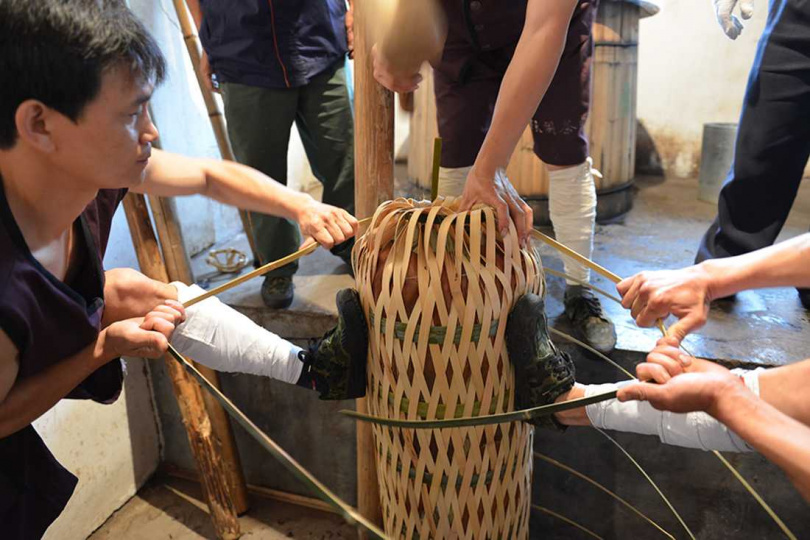 製作千兩茶將茶葉如擰花卷般擰成圓柱型,再用竹篾捆緊封口。(圖/吳德亮攝影)