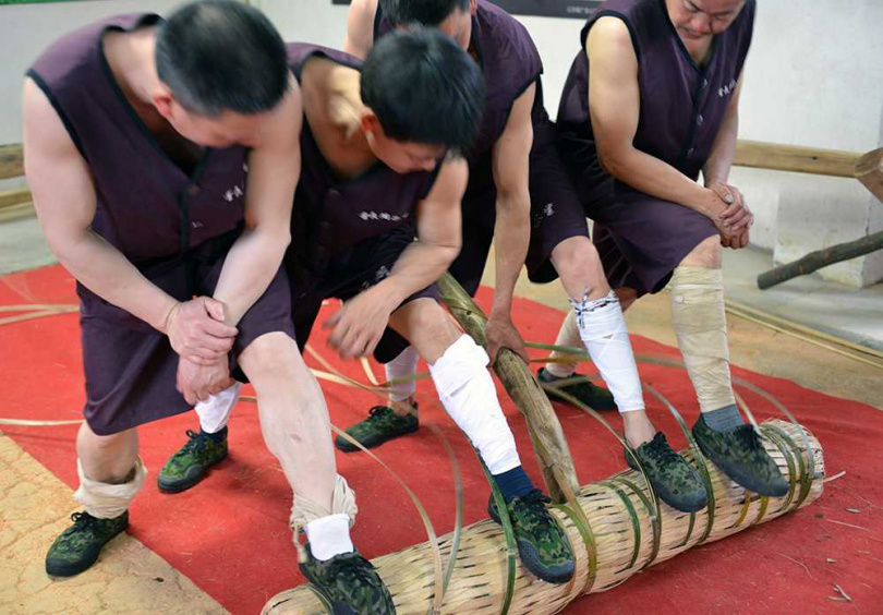 五名彪形大漢不停揮汗使力以竹片及竹條加以重壓捆紮。(圖/吳德亮攝影)