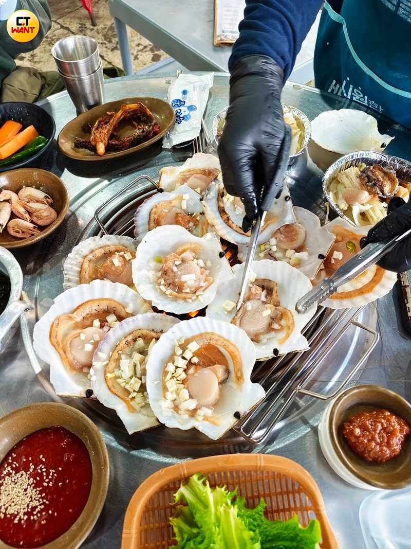 秀敏家的烤扇貝一字排開十分壯觀、口感新鮮彈牙,還會搭配金針菇、洋蔥一起烤。(圖/魏妤靜攝)