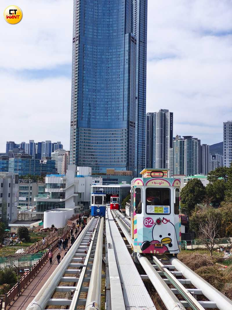除了一般素色的藍、紅、黃、綠四色膠囊列車,還有釜山吉祥物Boogie的特別版膠囊列車穿插其中。(圖/魏妤靜攝)