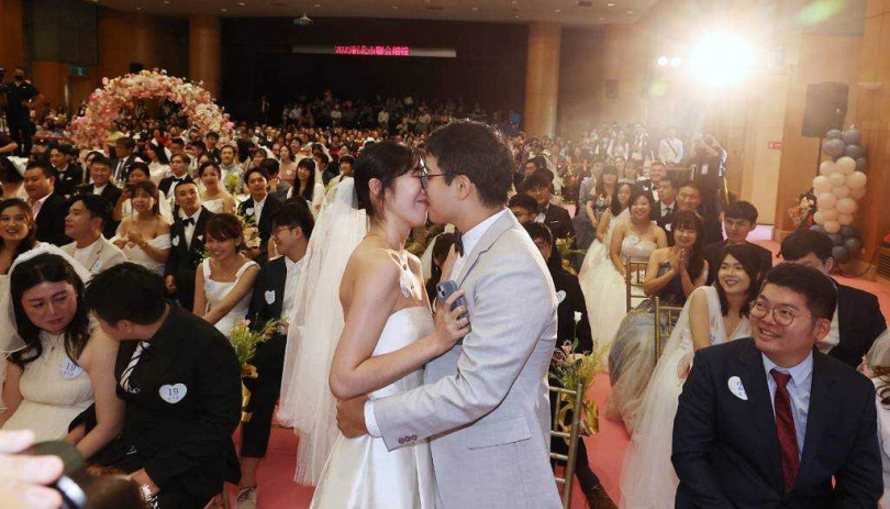 新北市政府19日舉行2025新北市聯合婚禮，第21組新人趙啟鈞（前中右）與馮思妤（前中左）幸運抽中峇里島5天4夜雙人蜜月旅遊的大獎，兩人按照抽獎規則擁吻十秒，羡煞其他新人。（圖／報系資料照）