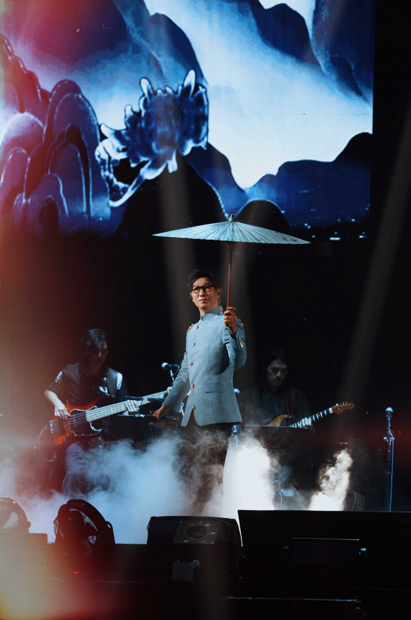 品冠撐著古色古香的油紙傘登台，在水墨畫般的舞台佈景中演唱〈想見你〉。（圖／種子音樂提供）