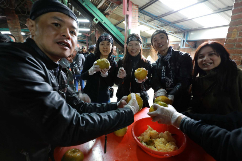 哈雷騎士們以特製的金屬圓筒在柑橘頂端開口挖果肉,是製作酸柑茶的第一步。(圖/吳德亮攝)