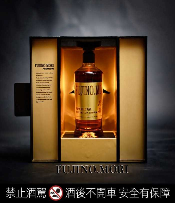 黑底金字禮盒搭配燈光效果，瓶身刻有富士靈峰圖樣，象徵尊榮與匠藝。金黃酒液在光影中閃爍，更添高貴氣質與收藏價值。（圖片提供／富士乃森）