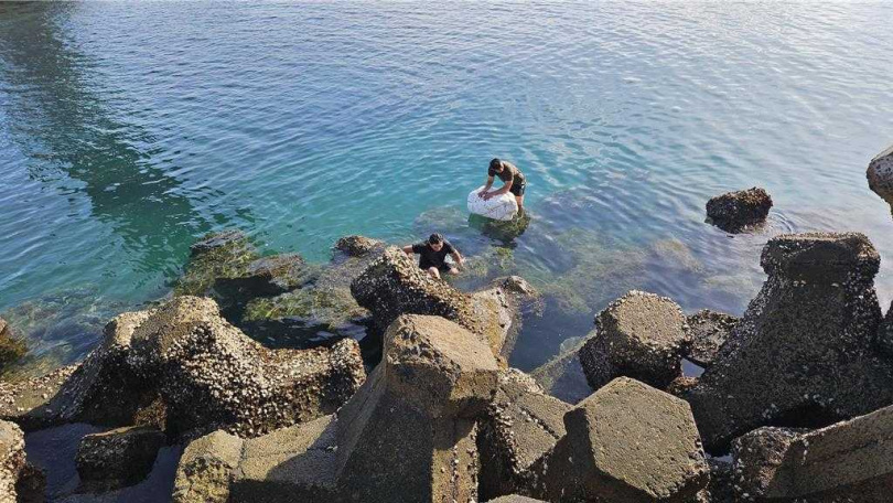   2025年8月12日澎湖縣／警消12日上午獲報趕往澎湖馬公市西瀛虹橋搶救橋上落海者（前），但到場時已被運動路過的澎防部本部連上士王博智（後）救起在消波塊上。（圖／翻攝畫面）