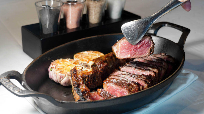 「澳洲銅樹農場純草飼老乳牛乾式熟成50天帶骨紐約克牛排」以薄切方式保留嫩度，還可搭配洲南鹽場竹鹽、玫瑰鹽、燻鹽與鹽之花提味。（套餐6,000元／600g，圖／魏妤靜攝）