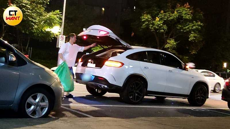 熊熊的老公忙著將汽車後車廂內的數袋衣服搬進店內。(圖/本刊攝影組)