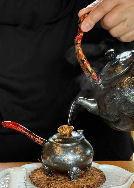 陳念舟以「盤古」燒水壺將水注入壺蓋開口的「三星堆注泉壺」內。（圖╱吳德亮攝）