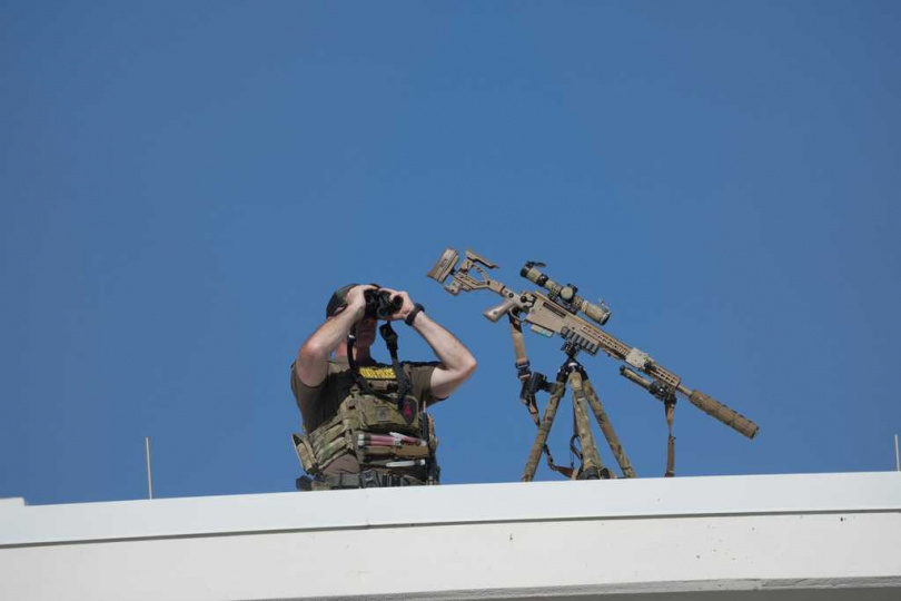 示意圖顯示一名狙擊手隱匿於高樓建築,準備對地面目標開火。