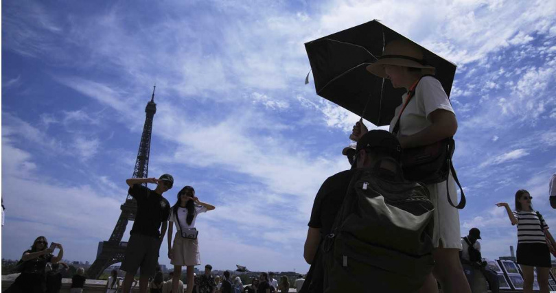 高溫襲法，遊客撐傘避陽，艾菲爾鐵塔頂樓因熱浪暫停開放。（圖／達志／美聯社）