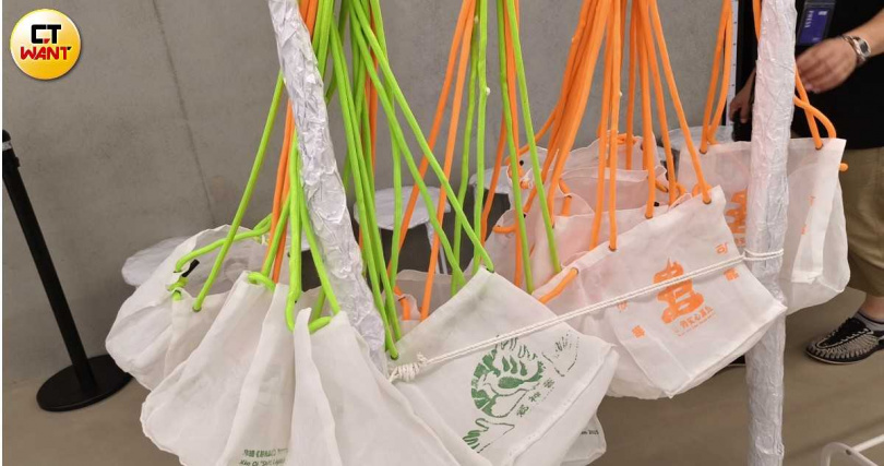 觀賞沉浸式作品〈移光盆地〉前須先拖鞋放入特製袋子中,袋身圖樣與背繩在黑暗中同樣會發出螢光。(圖/魏妤靜攝)