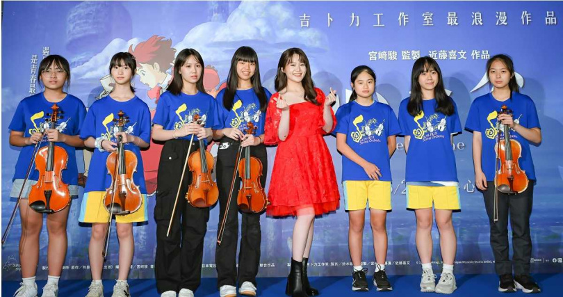 楊小黎穿著紅色蓬蓬裙洋裝，在學生簇擁下合照。（圖／甲上娛樂提供）