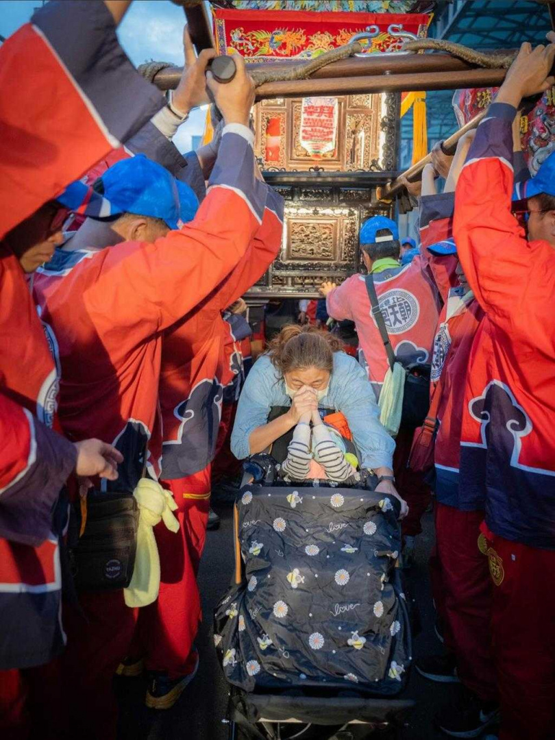 王媽媽20日在中西區西門路推著推車，與腦麻兒一起穿過北港媽神轎底。（圖／北港朝天宮攝影組提供）