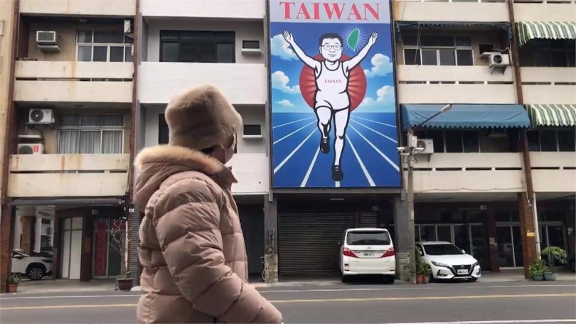 四層樓高的透天厝，外頭牆面懸掛巨大看板，底圖是藍天白雲，中間還有一名高舉雙手的慢跑男，吸引路過民眾的目光。（圖／民視新聞）