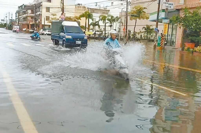 屏東東港海水倒灌,已連淹2天,汽、機車強行通過,濺起陣陣浪花。(東津里長葉而項提供/羅琦文屏東傳真)