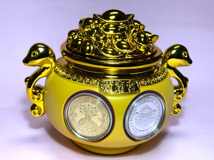 2025年「錢母」套幣外型設計為「聚寶盆」，兩側以黃金雙蛇護盆，「聚寶盆」正面為土地公神像、蛇年聚財靈氣，背面為金光閃閃的「聚寶盆」三個大字，頂蓋還能打開，可放入珍貴或重要的寶貴招財物品，象徵金銀財寶滿盆、滿缽、聚財。（圖／作者提供）