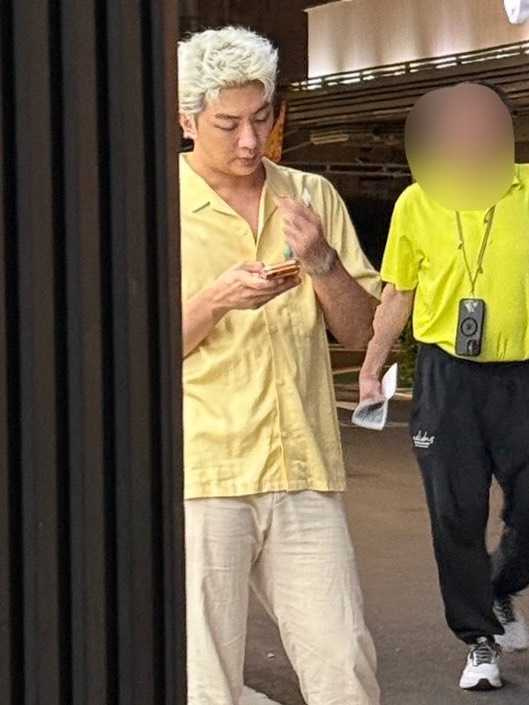 許明杰邊抽煙邊滑手機,一頭金髮很顯眼。(圖/讀者提供)