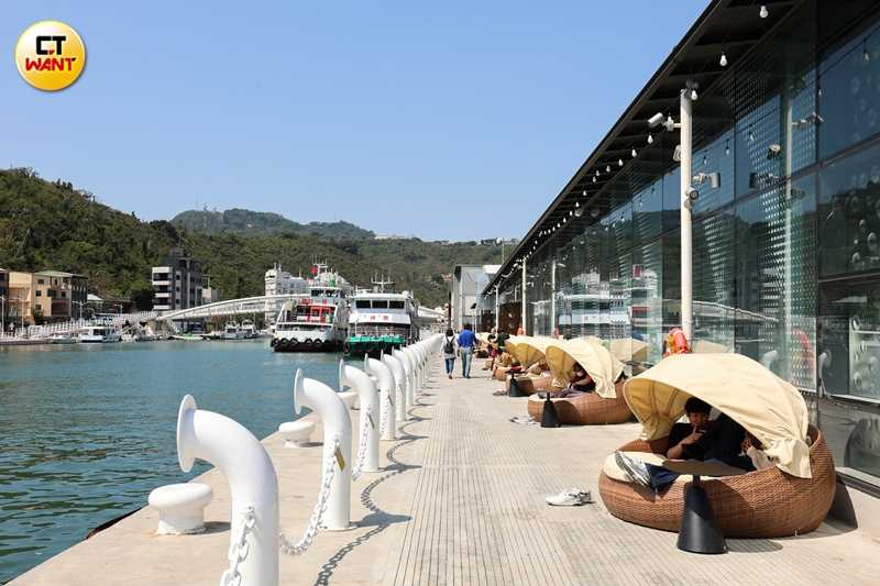 在新濱町海洋廚房戶外區域有類似營帳型態的座位區，與圖中情侶最愛的港邊賞景座位，黃昏時尤為搶手。（圖／林士傑攝）