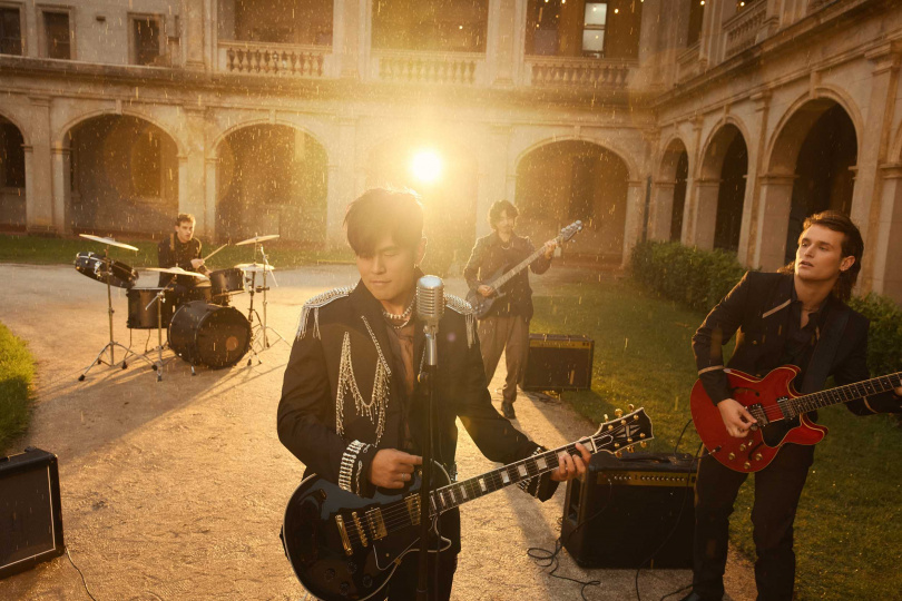 以一身龐克紳士搖滾風服裝入鏡的周杰倫，揹著吉他在雨中唱著〈誰稀罕〉。（圖／杰威爾提供）