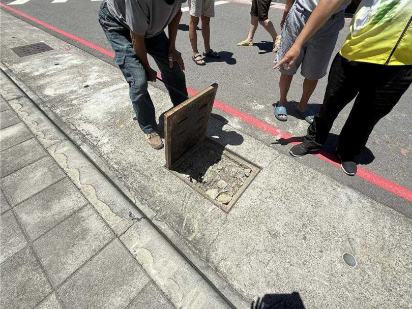 居民們徒手打開水溝蓋,裡面沒看到水,而是被土砂完全封死。(圖/中國時報紀爰攝)