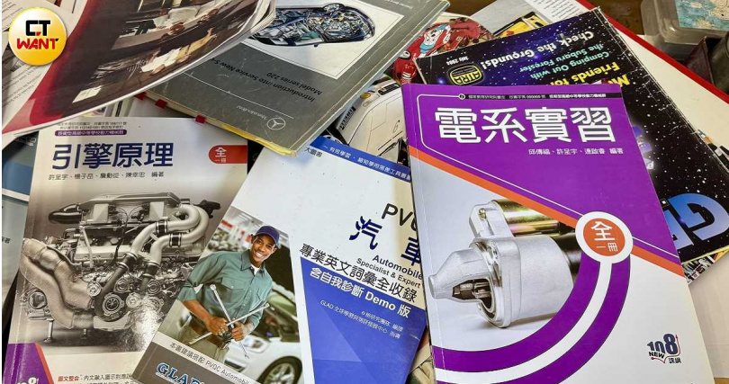 楊江山將錯誤版本教材攤開，數量多達十幾本，其中包含教育部統一規劃版本及學校自選教材。（圖／方萬民攝）