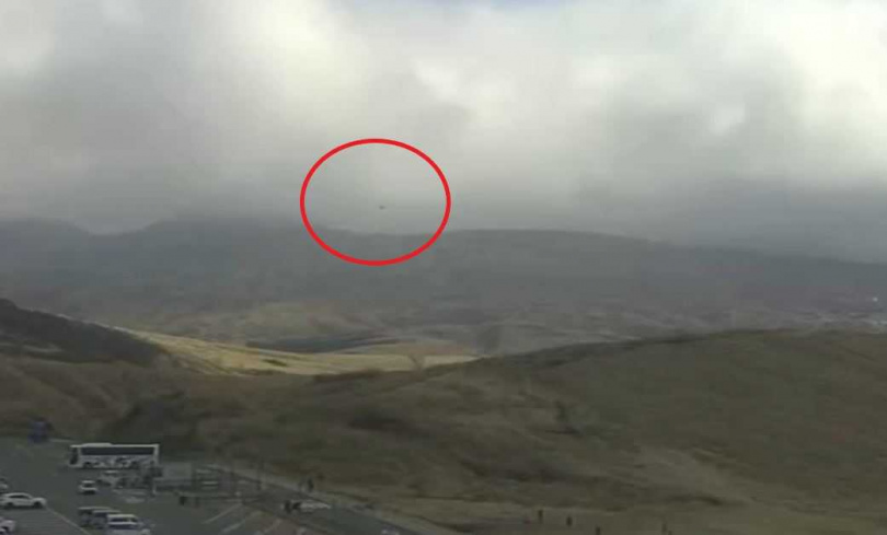 熊本放送在阿蘇火山博物館架設的即時攝影機，於上午11時許曾拍下疑似失聯直升機冒著黑煙、朝地面方向移動的畫面。（圖／翻攝自X）