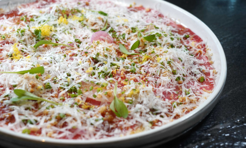 「韓式生牛肉」將薄切生牛肉融合鯷魚、芥末、帕達諾起司與香菜，以紫蘇油輕巧點綴，口感細膩滑順又不失清爽。（590元，圖／魏妤靜攝）