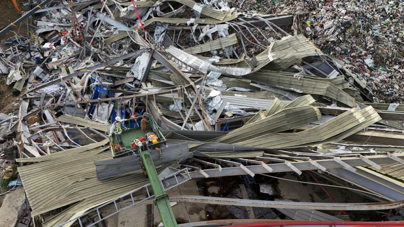 掩埋場內一座高達四層樓的垃圾山崩落，導致多名工人受困或罹難。