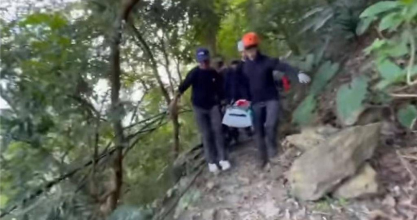 76歲許姓男子登棚集山，不慎滑落10公尺邊坡，左肩骨折無法行走，搜救人員以擔架將許翁抬下山，登山步道崎嶇狹窄，搜救人員抬著擔架行走困難。（圖／屏東縣消防局提供）