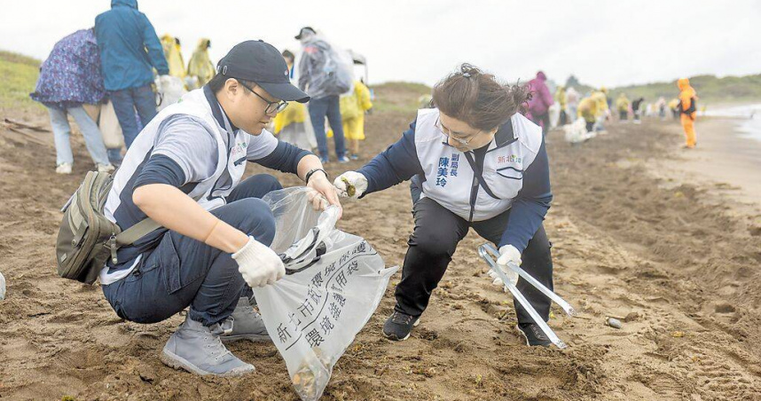 淨灘遇上颳風下雨，新北環保局副局長陳美玲（右）穿梭在沙灘上清理海廢。（圖／中國時報張鎧乙攝）