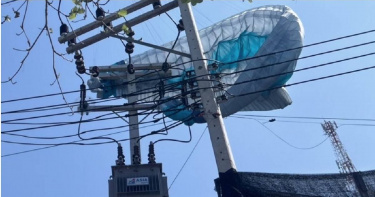 1名美國男子於泰國東岸1座知名觀光島嶼玩滑翔傘時，意外纏掛在高壓電線桿頂端。（圖／翻攝自《Khaosod English》）