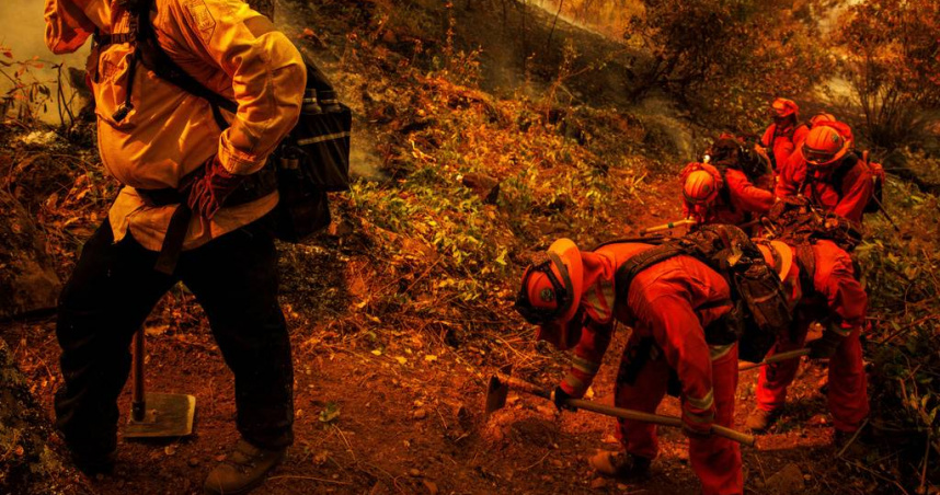 囚犯消防員正在火場中挖掘防火帶。（圖／達志／美聯社）