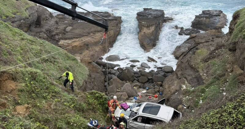 台2線瑞芳段14日上午發生轎車墜海事故，車輛卡在岸邊礁石間，消防人員利用吊臂將駕駛救出送醫。（圖／翻攝畫面）