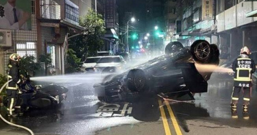 保時捷休旅車深夜在台中西屯翻覆起火，四輪朝天橫躺雙黃線，車底竄出火焰及濃煙。（圖／翻攝畫面）