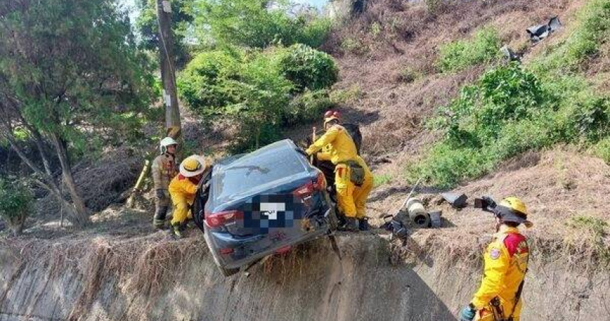 轎車撞電桿懸空卡邊坡。（圖／翻攝畫面）