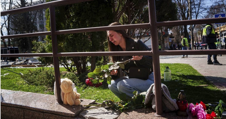俄羅斯襲擊烏克蘭蘇梅地區，女子哭著獻上鮮花和玩具。（圖／達志／美聯社，下同）