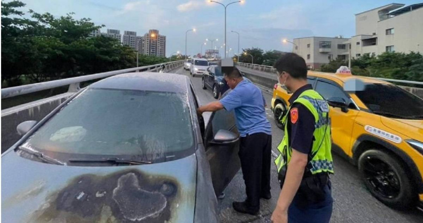 台中父子駕車行經高鐵陸橋時，引擎突竄白煙並冒烈火，警方趕抵指揮交通並持滅火器救火。（圖／翻攝畫面）