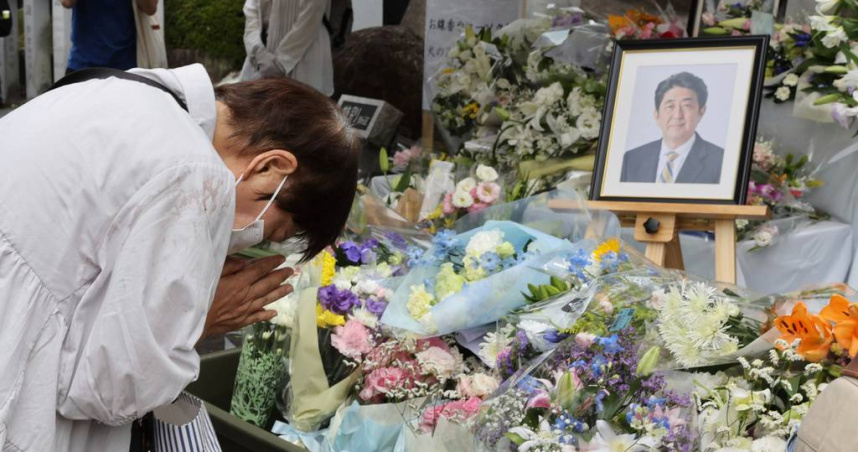 日本前首相安倍晉三逝世一周年之際，民眾在奈良縣奈良市一處墓地的紀念碑前默哀。（圖／達志／美聯社）