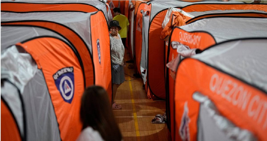 中度颱風「鳳凰」9日登陸菲律賓奎松市（Quezon City），1名女子走過體育館的帳篷。（圖／達志／美聯社）