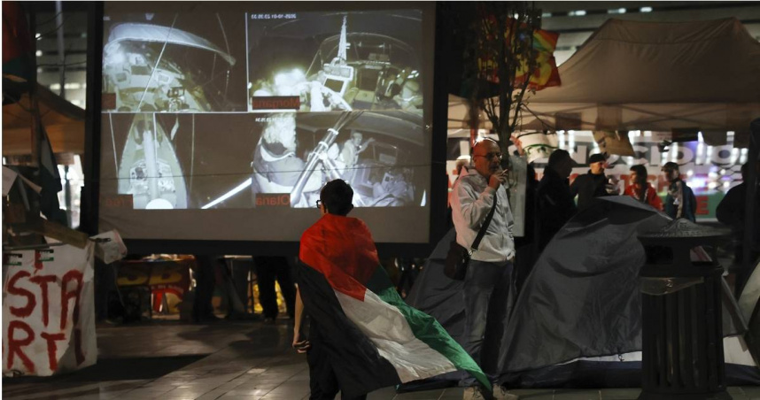 一名身披巴勒斯坦國旗的示威者在羅馬觀看船隊直播。（圖／達志／美聯社）