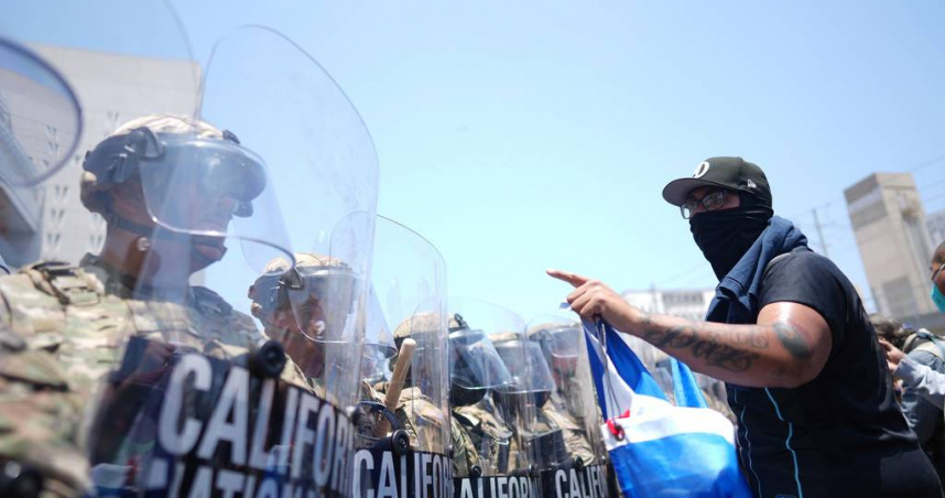一名抗議者在洛杉磯市中心的大都會拘留中心與國民兵對峙。（圖／達志／美聯社）
