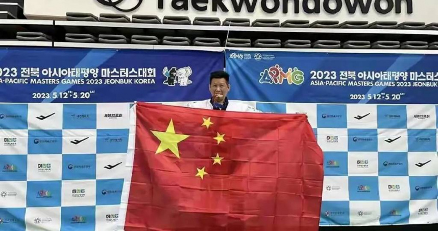 跆拳道選手李東憲於亞太壯年運動會獲得銅牌，但在領獎時高舉五星旗，引發爭議。（圖／翻攝自微博）